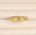Front detail of the gold stacking ring in a cream jewellery tray, showing the repeating textured pattern.