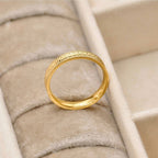 Angled view of the gold stacking ring in a cream jewellery tray, showing the polished interior and patterned band.