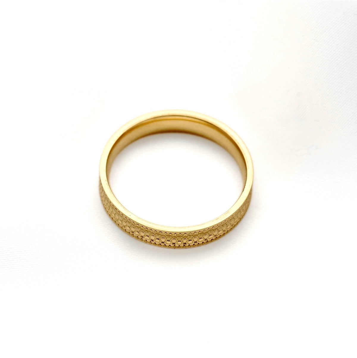 Gold stacking ring lying flat on a white background, showing its circular shape and smooth interior.